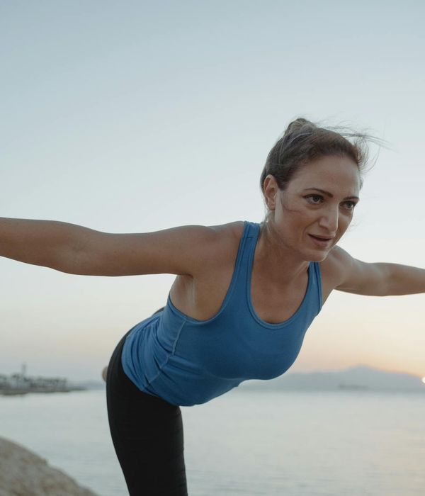 Woman stretching gracefully outdoors in the morning sun.
